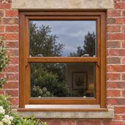 Golden Oak uPVC sliding sash window on a red brick house