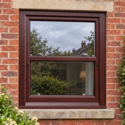 Rosewood uPVC sliding sash window on a red brick house