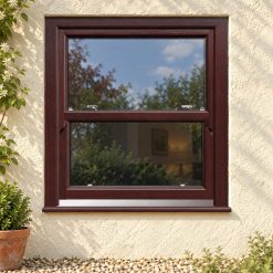 Rosewood uPVC sliding sash window on a rendered cottage
