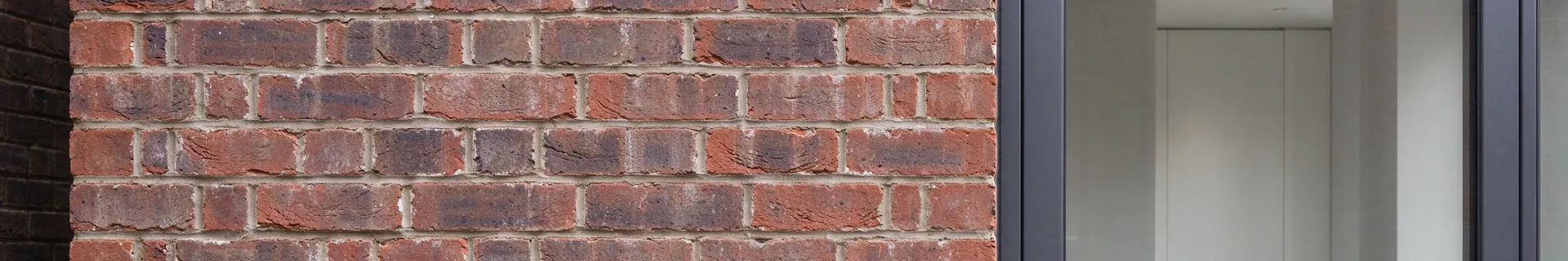 Anthracite grey aluminium window in a red brick wall
