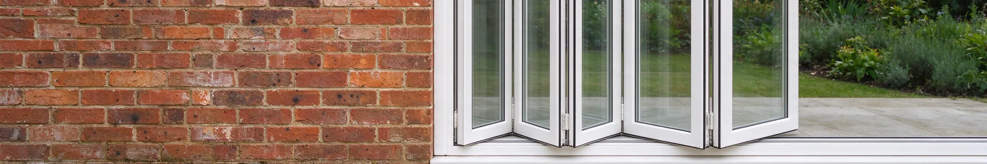 White bifolding doors folded open onto a garden