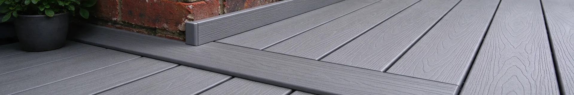 Grey composite decking next to a red brick wall